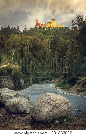 View of Pena Palace in Sintra, Portugal, on top of a hill with a road in the foreground