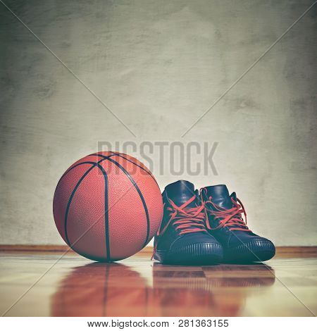 Basketball Background. A Pair Of Basketball Shoes On A Hardwood Floor Next To A Basketball. Retro To