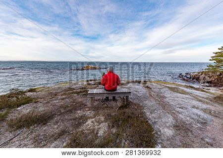 Man In Red Jacket Sitting On A Bench