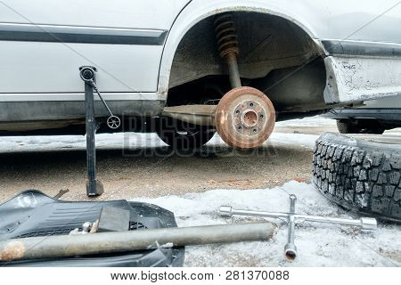 Car Repairs. Replacement Of The Punched Wheel. Car Stands On The Jack. On The Ground With Snow Work 