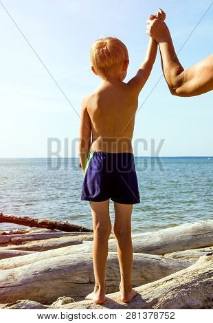 Child Stand On The Log With Hand Up On The Sea Background