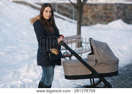 Young Mother Walking With Her Baby In Pram. Beautiful Stoller. Winter Photosession