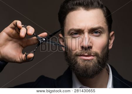 Portrait Of Stylish Hipster Man With Beard Holding Scissors Near Face. Barber Scissors And Straight