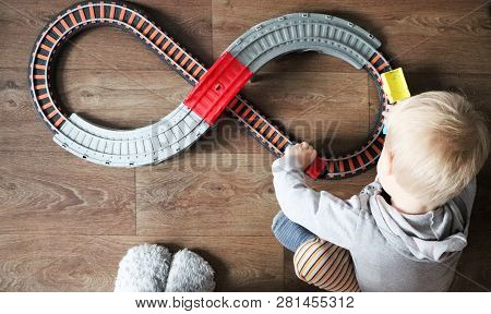 A Little Boy Plays A Children's Railway. Mom Is Watching Her Son From Above. The Child Is Fascinated