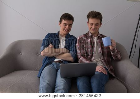 Handsome Young Men Using Laptop To Watch Movie. Couple Of Teengers Watching Something On Computer To