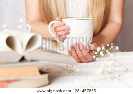 A Cup Of Tea In Womens Hands. Cozy Concept For Spring Morning. Spring Flower Tea In A White Cup On T