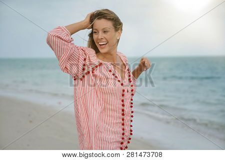 Funloving young woman lauhging at the beach
