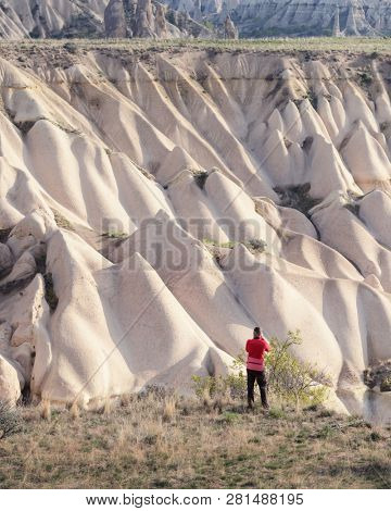 Amazing day in Cappadocia mountains, Turkey. Photographer in red jacket taking photo of amazing hills. Landscape photography