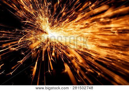 Bright Orange And Yellow Sparks On A Black Background. A Stream Of Bright Sparks From Metal Cutting