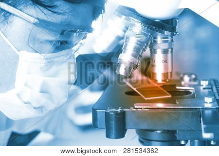 Hands Of Young Asian Man And White Microscope In Science Laboratory With Red Liquid And Dropper For