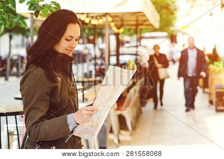 Woman Tourist Walking. Attractive Young Female Tourist Is Exploring New City. Woman With Map In Hand