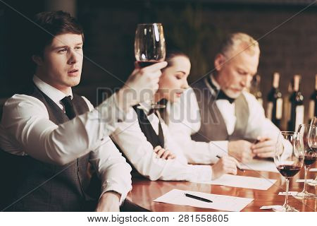 Young Experienced Sommelier Looks At Sediment Of Wine In Glass. Wine Tasting. Confident Sommelier Ch