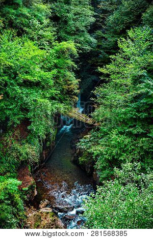 Wooden Bridge Over A Mountain River. Eastern Abkhazia. Near The Town Of Tkvarcheli. The Kambarka Dis