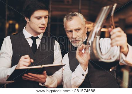 Two Men Sommelier Tasting Wine In Restaurant Looking At Decanter With Wine. Tasting Of Elite Drinks.