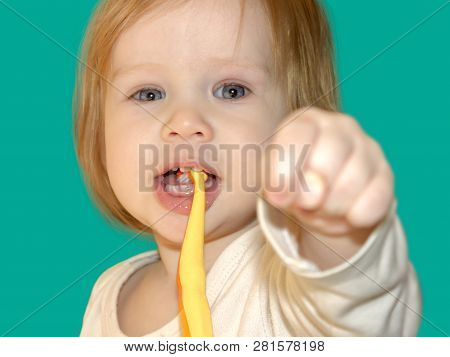 Little Baby Girl Dabbles And Has Fun While Learning To Brush Her First Teeth. The Child Shows The Fi