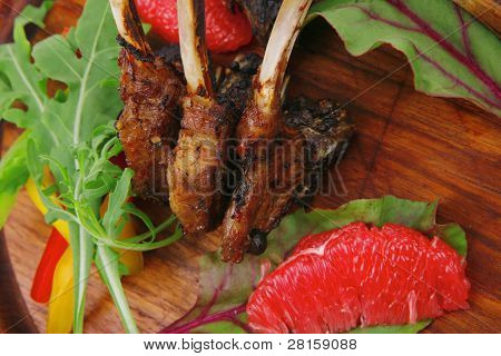 cibo di carne: arrosto di costole su piastra di legno con foglie di rucola e pompelmo isolata over white backgro
