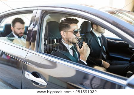 Hispanic Security Person Using Radio Transceiver While Transporting Businessman In Car