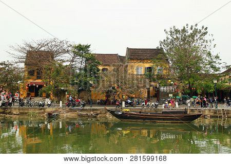 Hoi An, Vietnam - February 12, 2018: View On The Embankment Of Thu Bon River With Yellow Buildings A