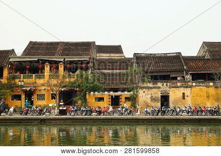 Hoi An, Vietnam - February 12, 2018: The Embankment Of Thu Bon River With Yellow Buildings And Tradi