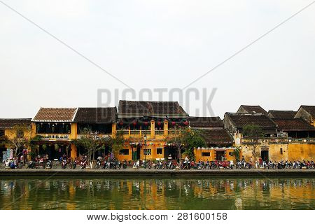 Hoi An, Vietnam - February 12, 2018: The Embankment Of Thu Bon River With Yellow Buildings And Tradi