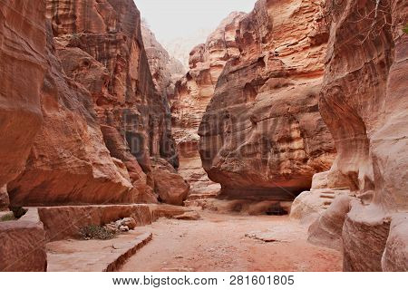 The Siq - Narrow Entrance To The Ancient Nabatean City Of Petra With Wide Path In Gorge Between High