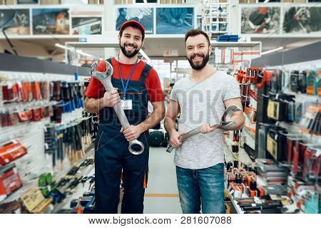 Salesman With Customer In Power Tools Store. Salesman Is Bearded Caucasian Man In Uniform. Customer 