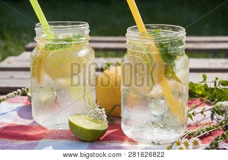Cold Refreshing Drink In Glass Jar With Slices Of Lemons And Limes. Decorated With Fresh Mint Herbs 