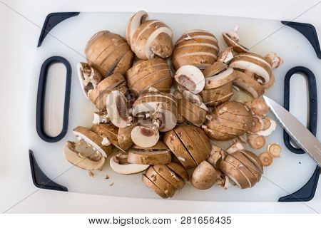 A Pile Of Sliced Chestnut Mushrroms (agaricus Bisporus) On A White Chopping Board