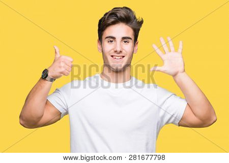 Young handsome man wearing white t-shirt over isolated background showing and pointing up with fingers number six while smiling confident and happy.