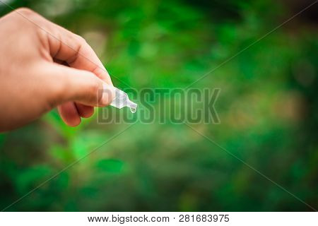 Man Holding And Droping Eye Drop Against Natural Background
