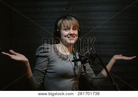 Confused Woman A Singer In A Headphones Is Guiltily Spreading Hands In A Sound Recording Studio Room