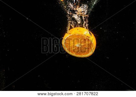 Half Of An Orange Falling On Black Background