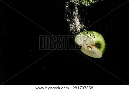 Half Of Green Apple Splashes Water While It Falls