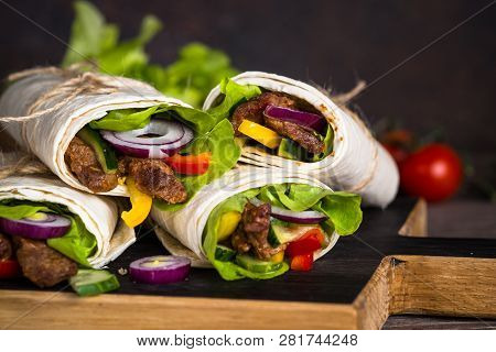 Burritos Tortilla Wraps With Beef And Vegetables On Wooden Cutting Board. Traditional Latin American