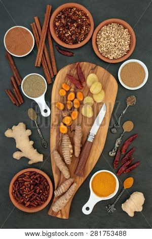 Spices for weight loss and slimming with fresh and dried turmeric, cumin, ginger, chilli, cinnamon and gymnema sylvestre used to suppress appetite. Top view on slate background.