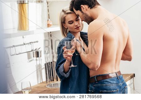 Selective Focus Of Attractive Girlfriend And Handsome Boyfriend Holding Wine Glass And Hugging At Ki