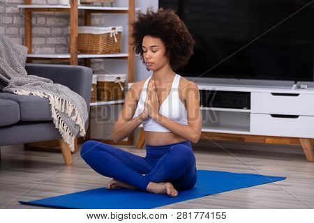Young African Woman Sitting On Floor In The Prayer Position Mediating