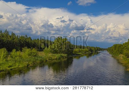 Summer Landscape: Quiet Narrow River Surrounded By Green Forest Against The Blue Cloudy Sky. Ukraine