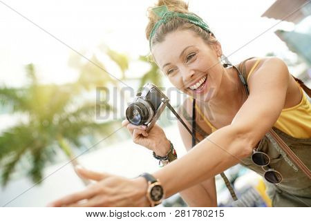 Stylish young woman taking photos with vintage camera in urban setting