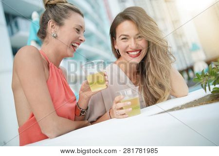 Two attractive funloving friends partying with drinks on rooftop bar in city