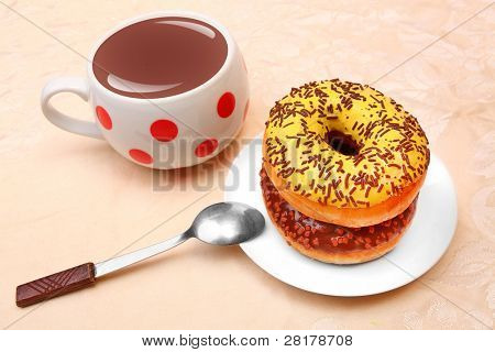 Süßes Frühstück. Tasse Schokolade und zwei verglaste Donut mit Kakao und Vanille besprengt.