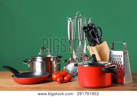 Set Of Clean Cookware And Utensils On Table Against Color Background