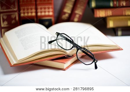 Stack Of Books With Black Glasses Placed On The Open Book On The White Background, Cconcept Educatio