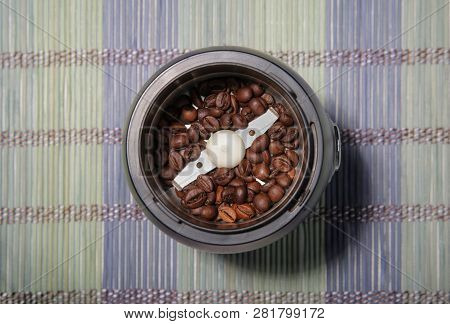 Coffee Beans In A Coffee Grinder. Bamboo Mat. Closeup.