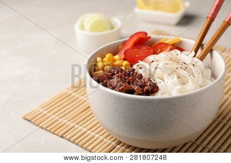 Bowl With Rice Noodles, Meat And Vegetables On Table