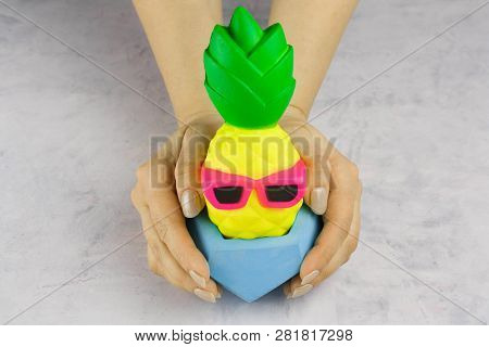 Girl's Hands With Bright Pineapple With Sunglasses In Concrete Pot On White Background