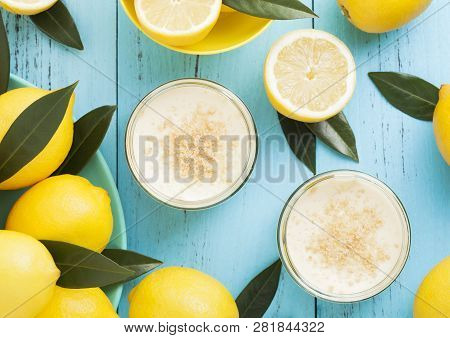 Glass Jar With Lemon Cheesecake With Fresh Lemons On Bluw Wooden Background