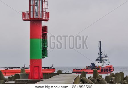 Red Tugboat On Roadstead - A Small Ship Departs From The Port Of Swinoujście By Towing A Barge