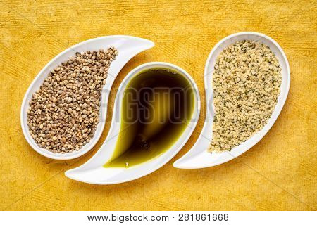 dry hemp seeds, hearts and oil in small teardrop bowls against red textured paper