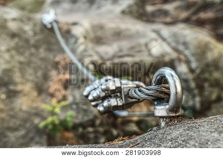 Stainless Twisted Rope Anchored In Rocky Wall. Stair Climbing And Iron Rope On Mountain Via Ferrata